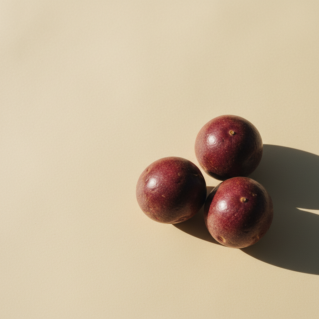 Three whole ripe passionfruits on warm cream paper